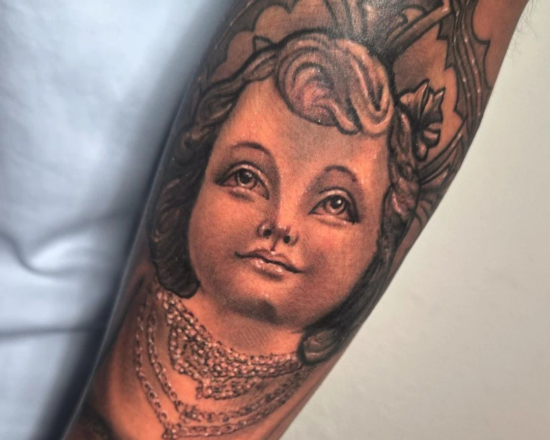Cherub angel face tattoo in black and gray realism on forearm by RCD Ink Tacoma